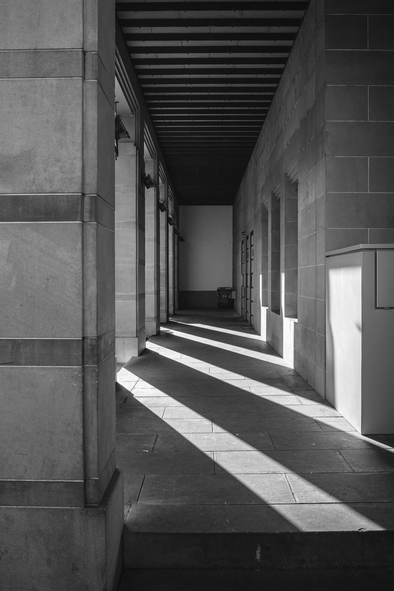 A stone colonnade with bands of sunlight across the floor