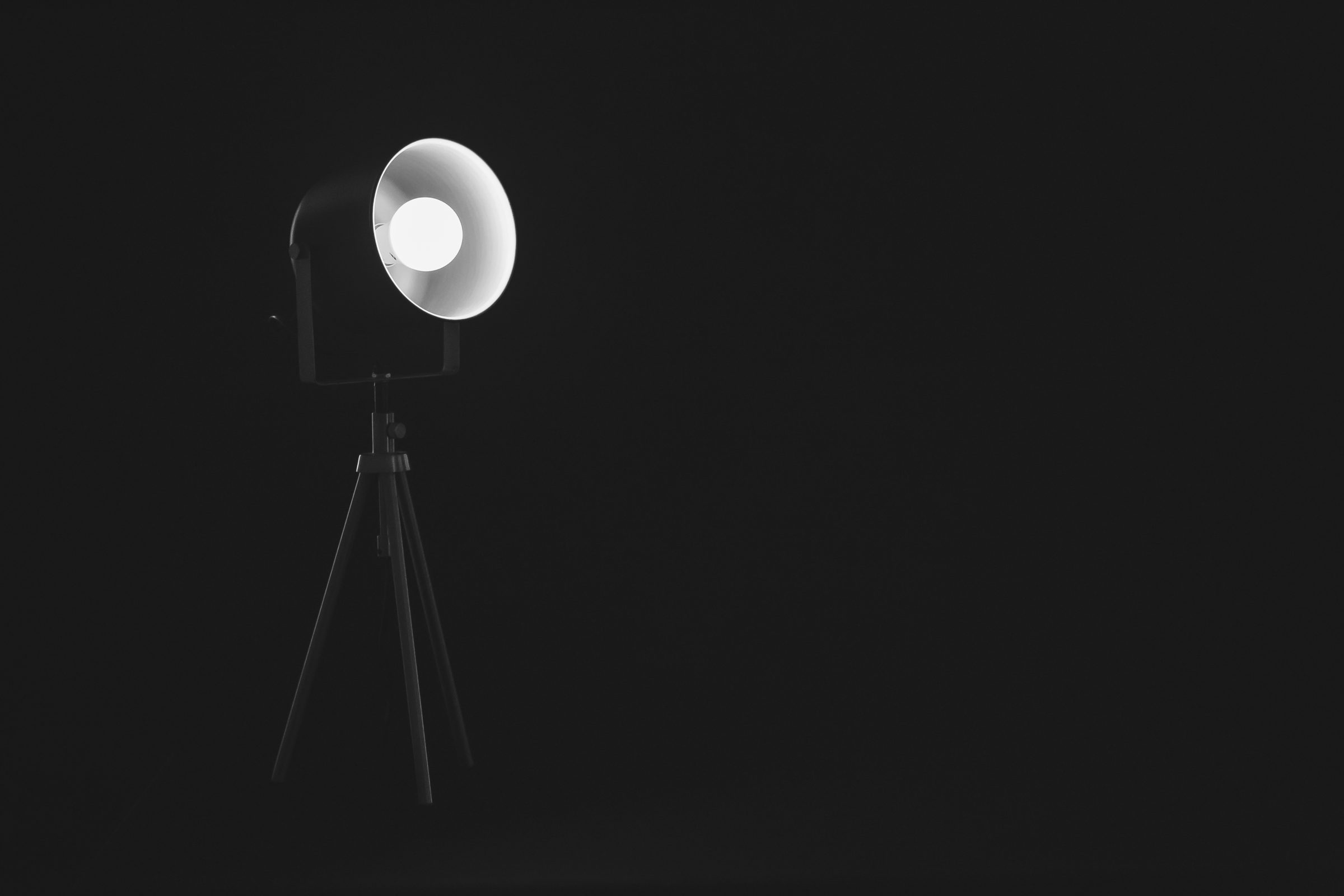 A studio lamp on a tripod glowing in a dark room
