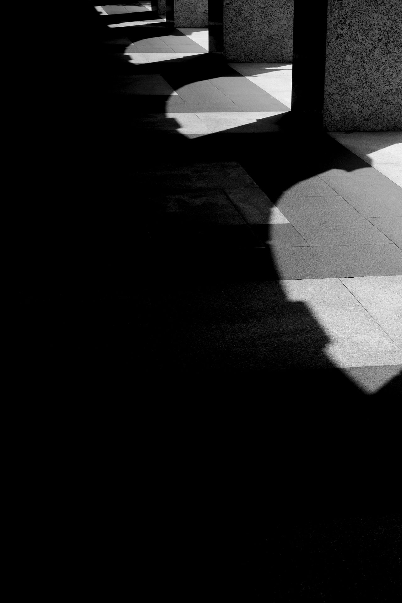 Arched shadows falling across a stone colonnade floor