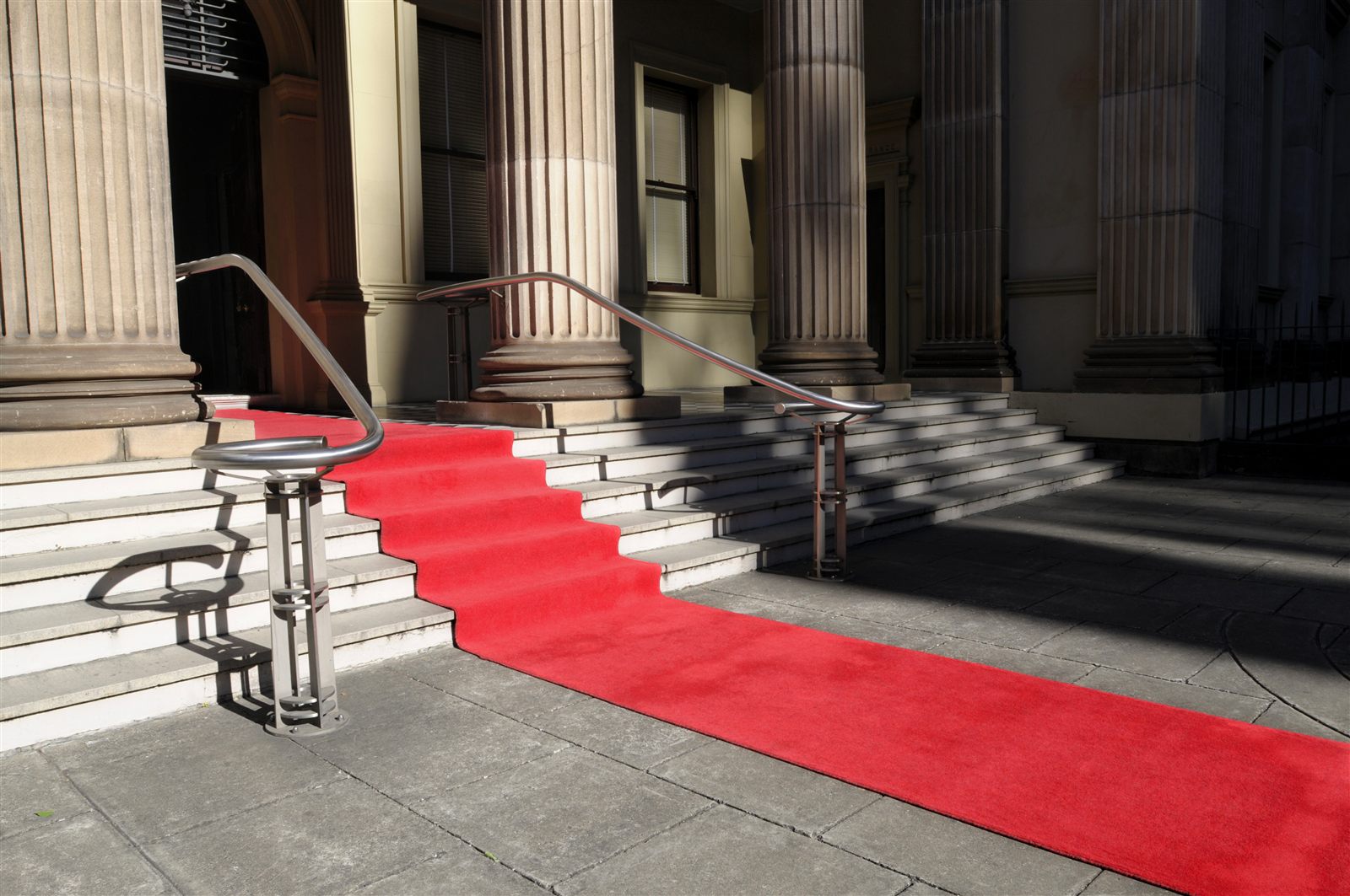 A red carpet and rail before a columned entrance