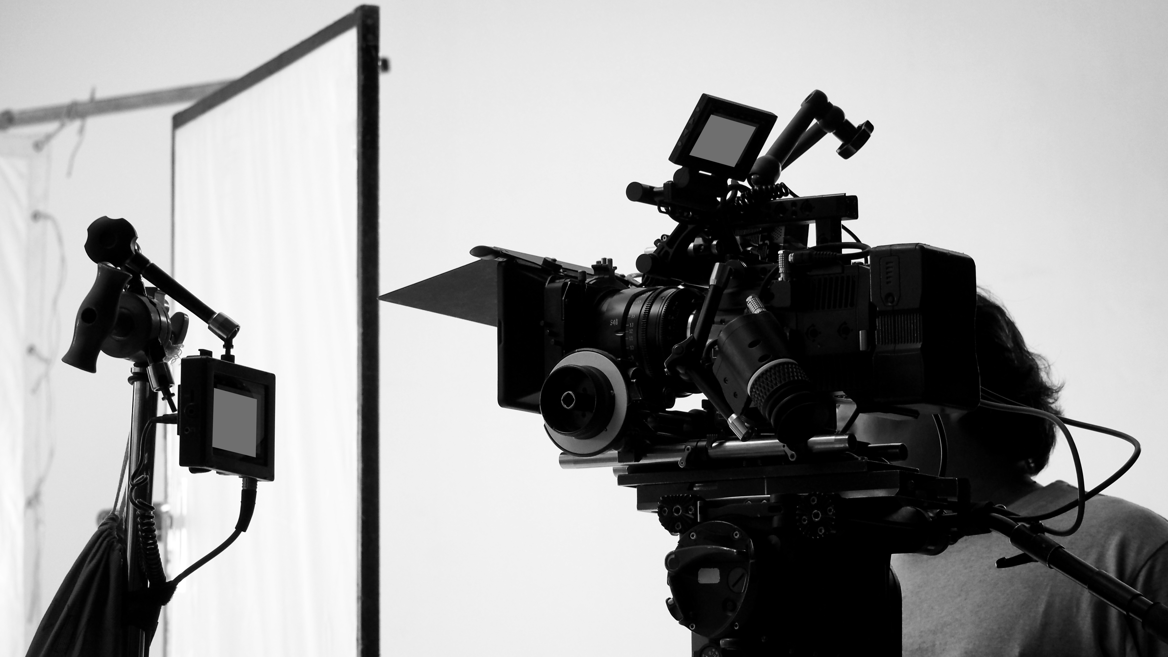 A cinema camera on a tripod against a quiet studio backdrop, the finished work about to begin.
