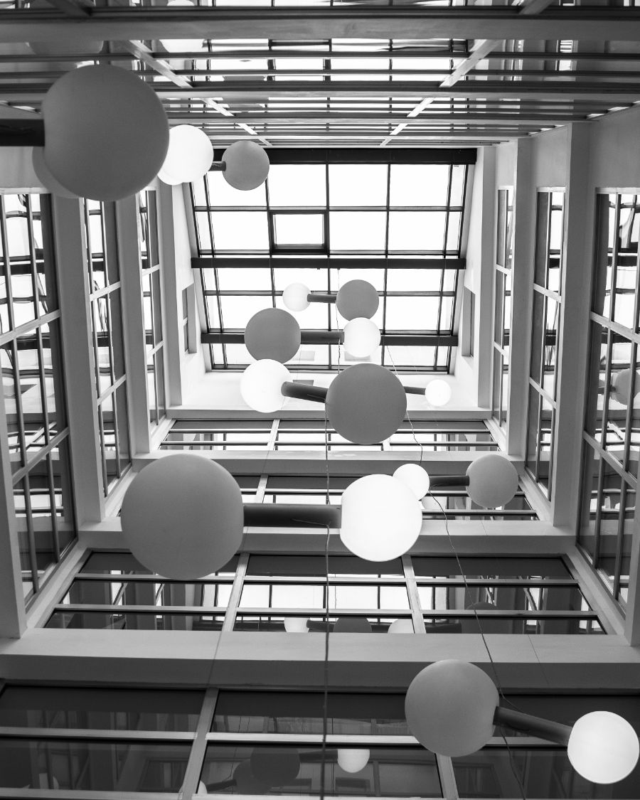 A glass atrium with suspended spherical lights seen from below