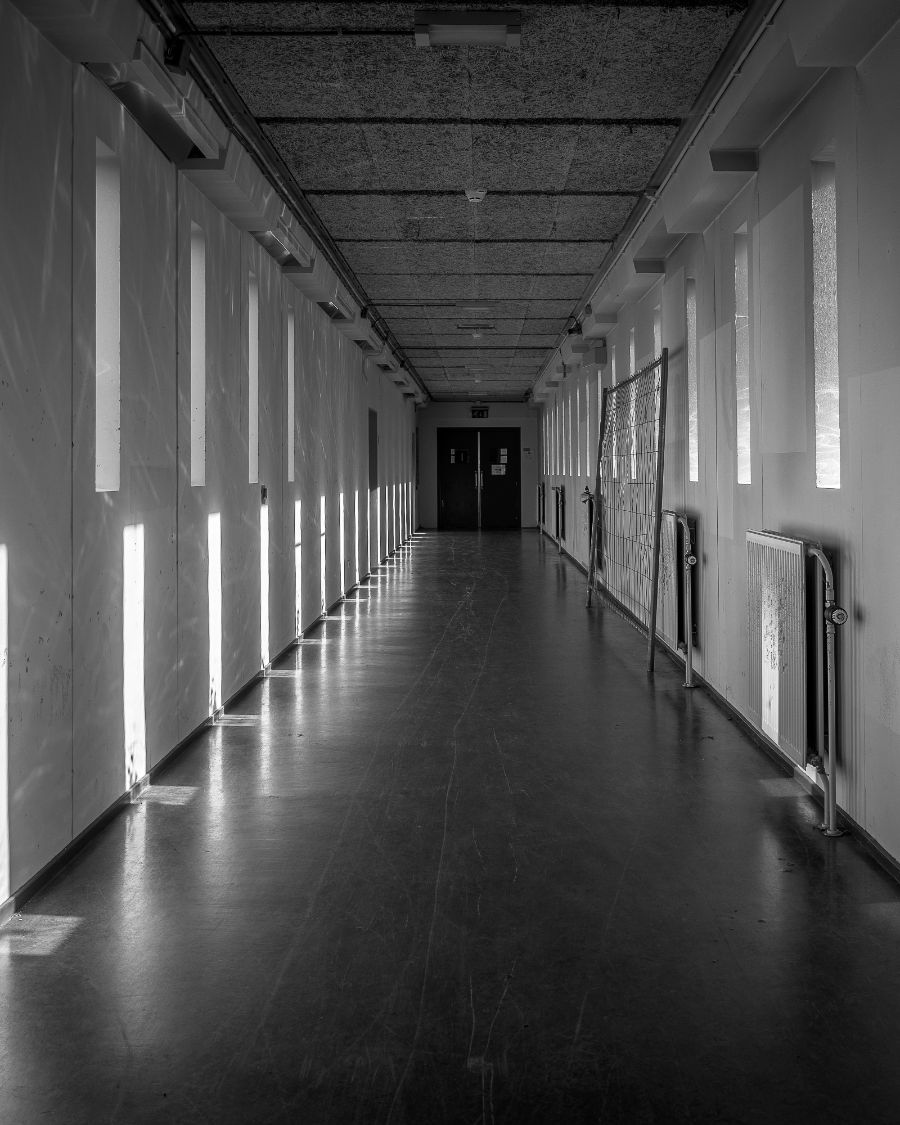 A long empty corridor lit by tall windows