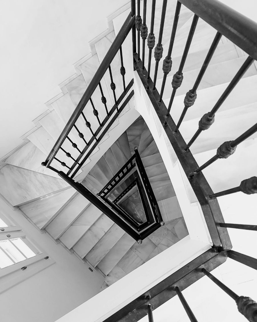 A square stairwell with a dark handrail seen from above