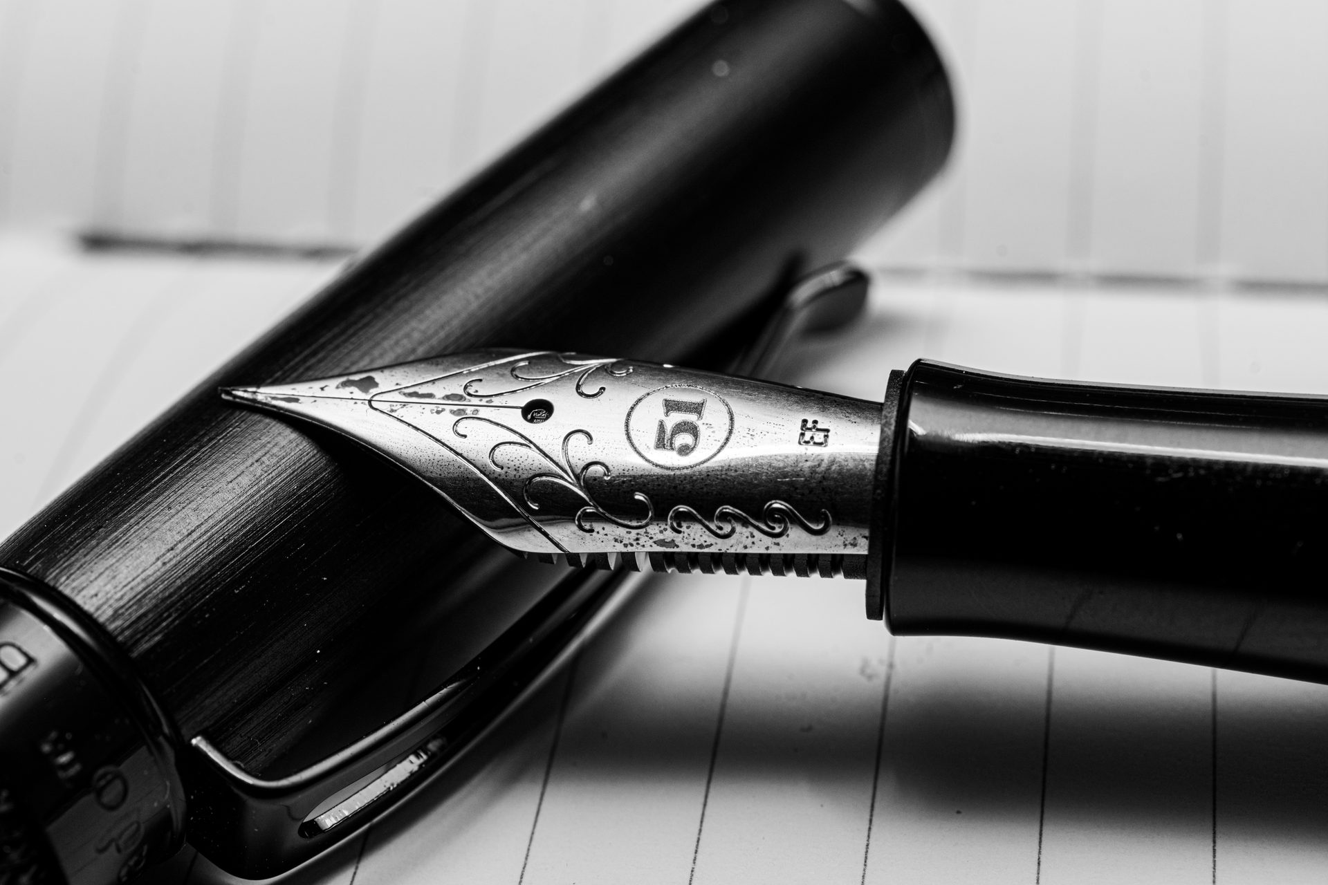 A fountain pen nib resting on lined paper