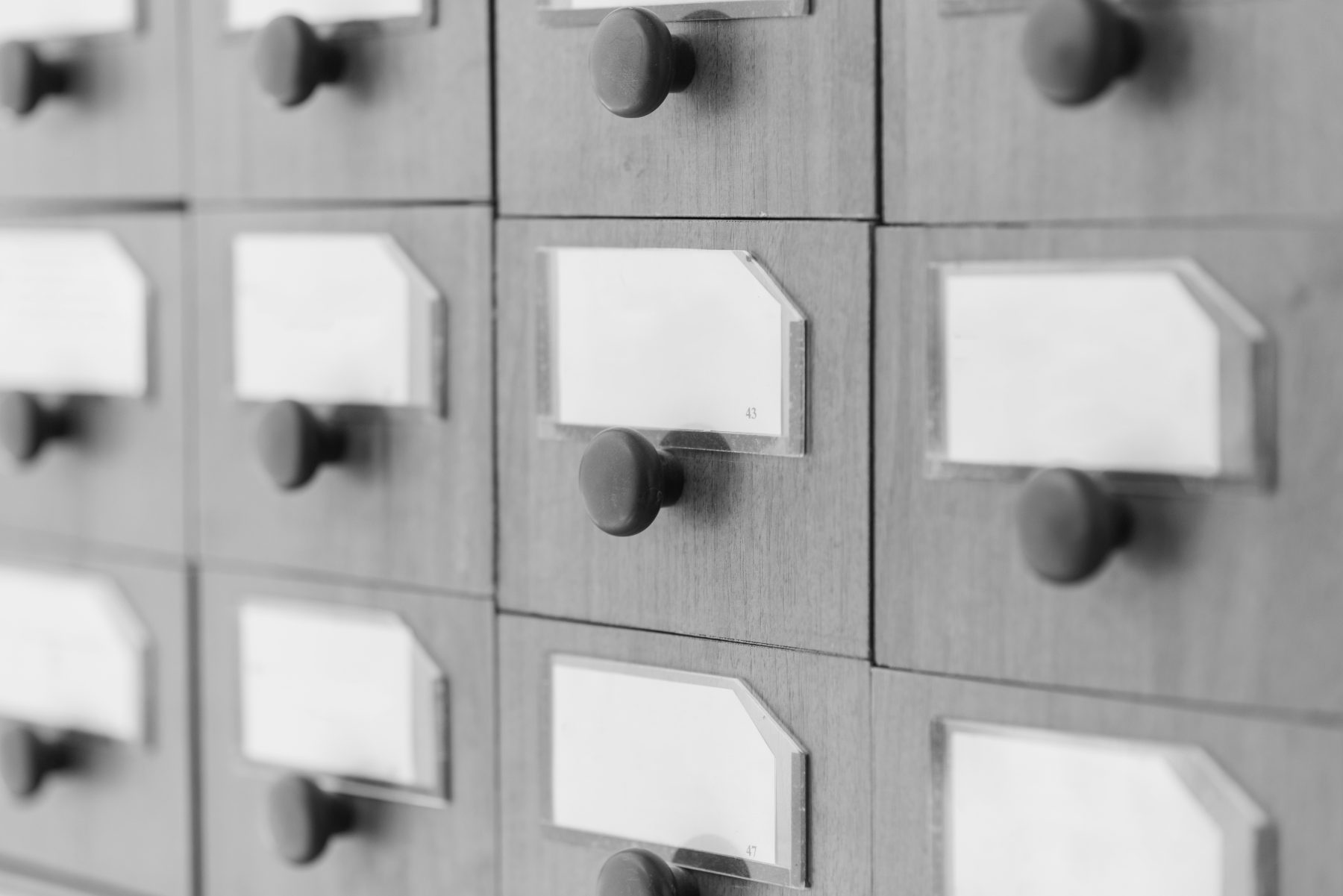 Rows of labelled wooden catalogue drawers, in black and white