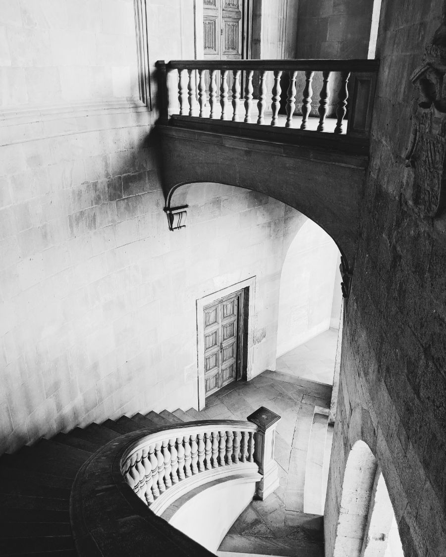 A carved stone balcony above a curving palace staircase
