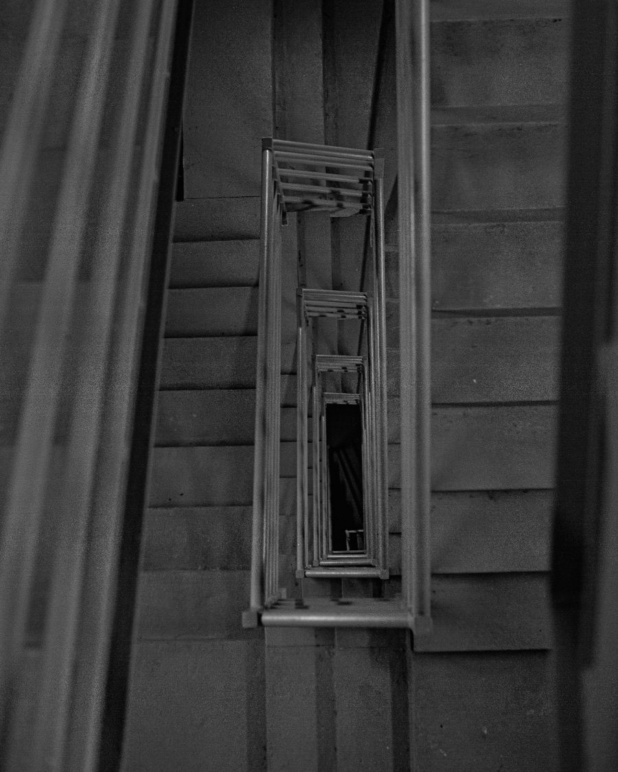 A narrow stairwell descending between grey walls