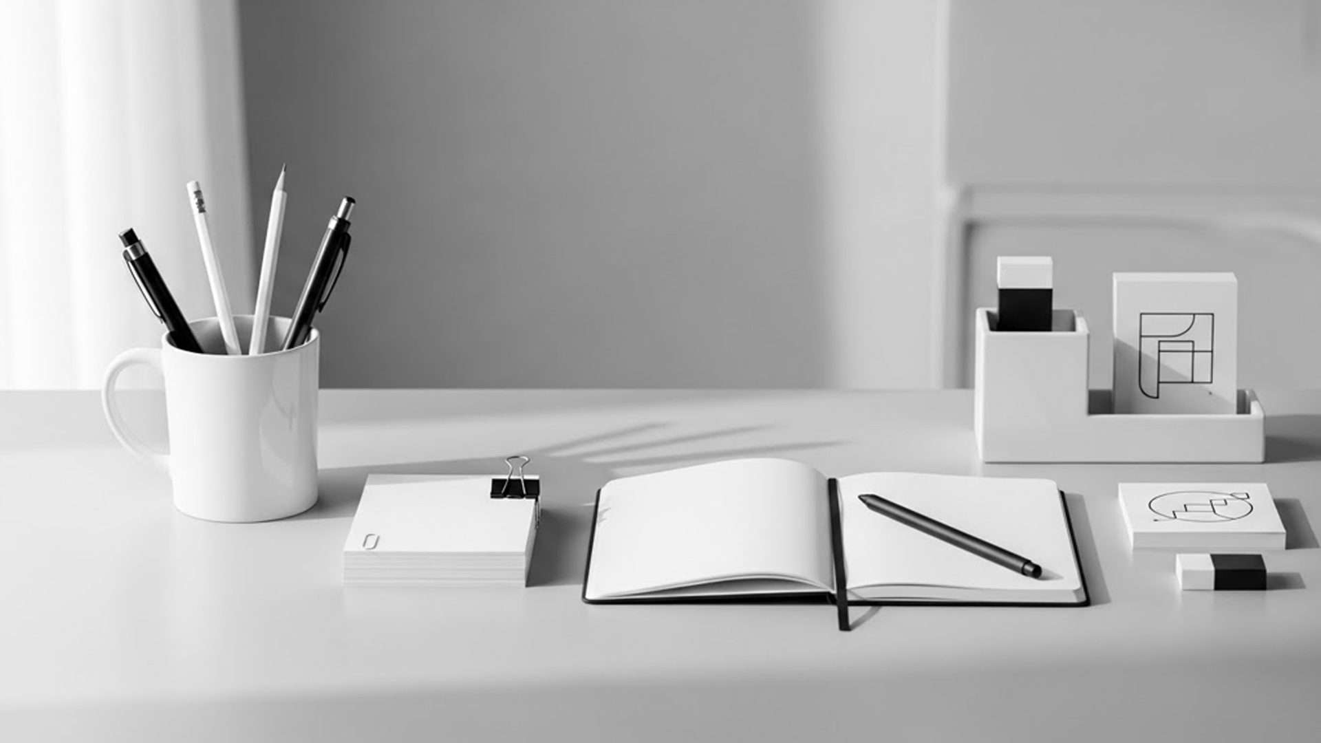 A white desk with a notebook, pencils and cards