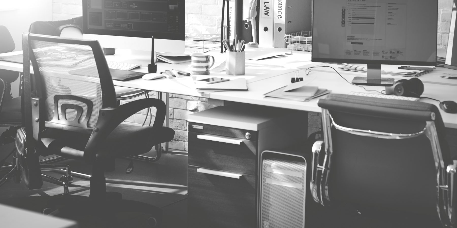 An empty office workspace with computers in black and white