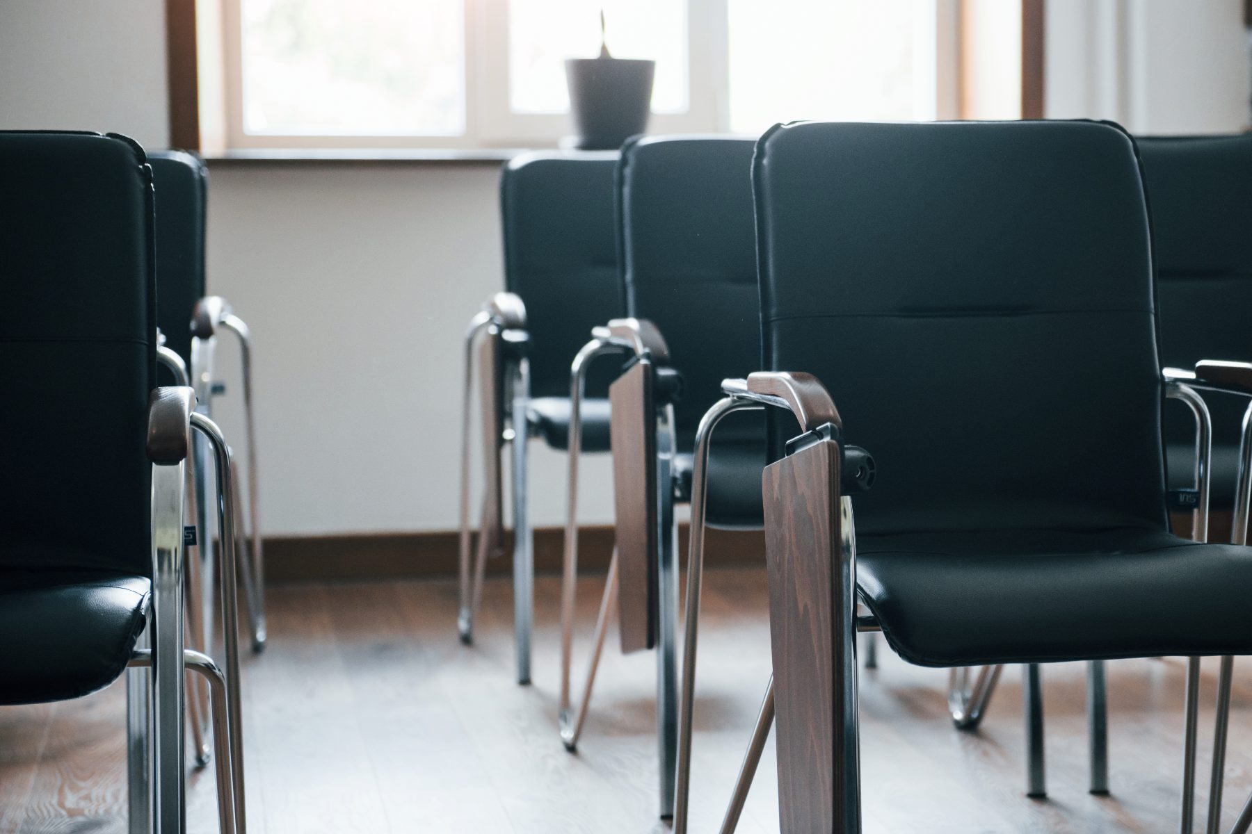 An empty classroom with rows of black chairs in daylight