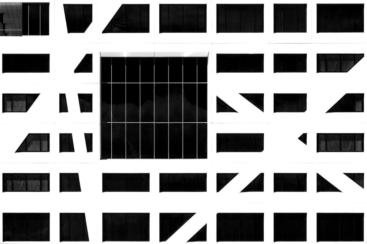 A white facade crossed by diagonal beams between dark windows