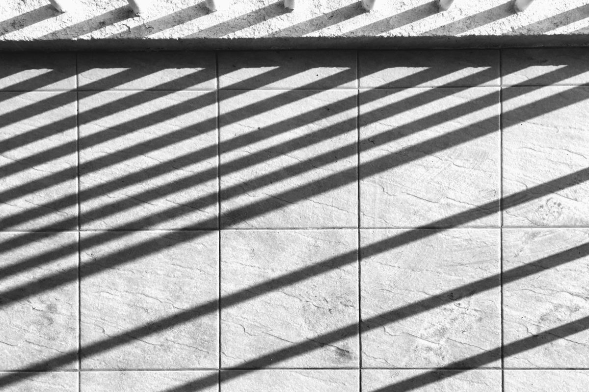 Diagonal bands of shadow falling across a pale stone wall